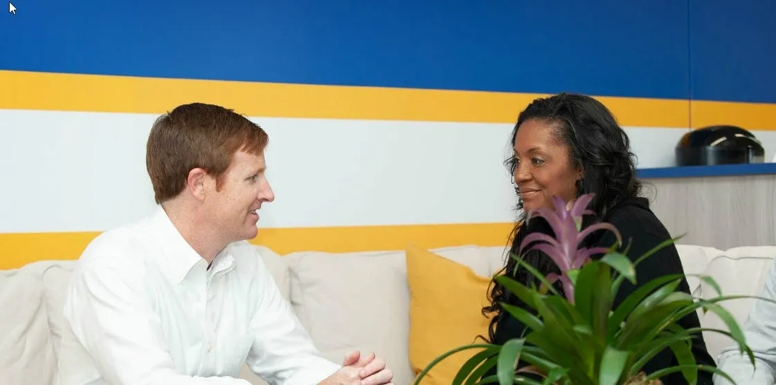 A man and woman sitting on a couch talking.