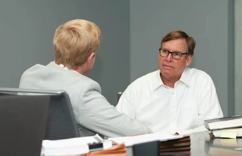 A man and woman shaking hands in an office.